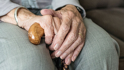 Hands of elderly woman with walking stick