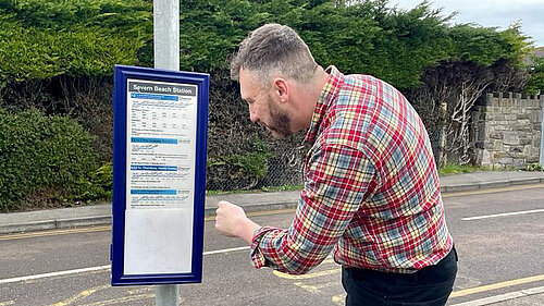 Cllr Simon Johnson reading bus timetable